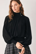 Front view: black draped knit top with high collar and small button detail at neckline