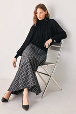 Black draped knit top with high neck, buttoned collar, and oversized balloon sleeves