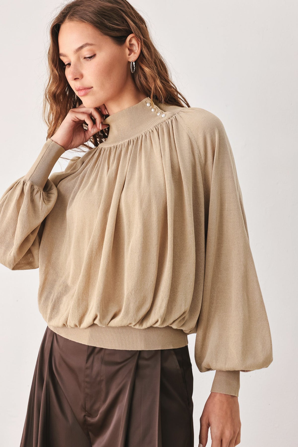 Taupe draped knit top with high neck, buttoned collar, and long balloon sleeves