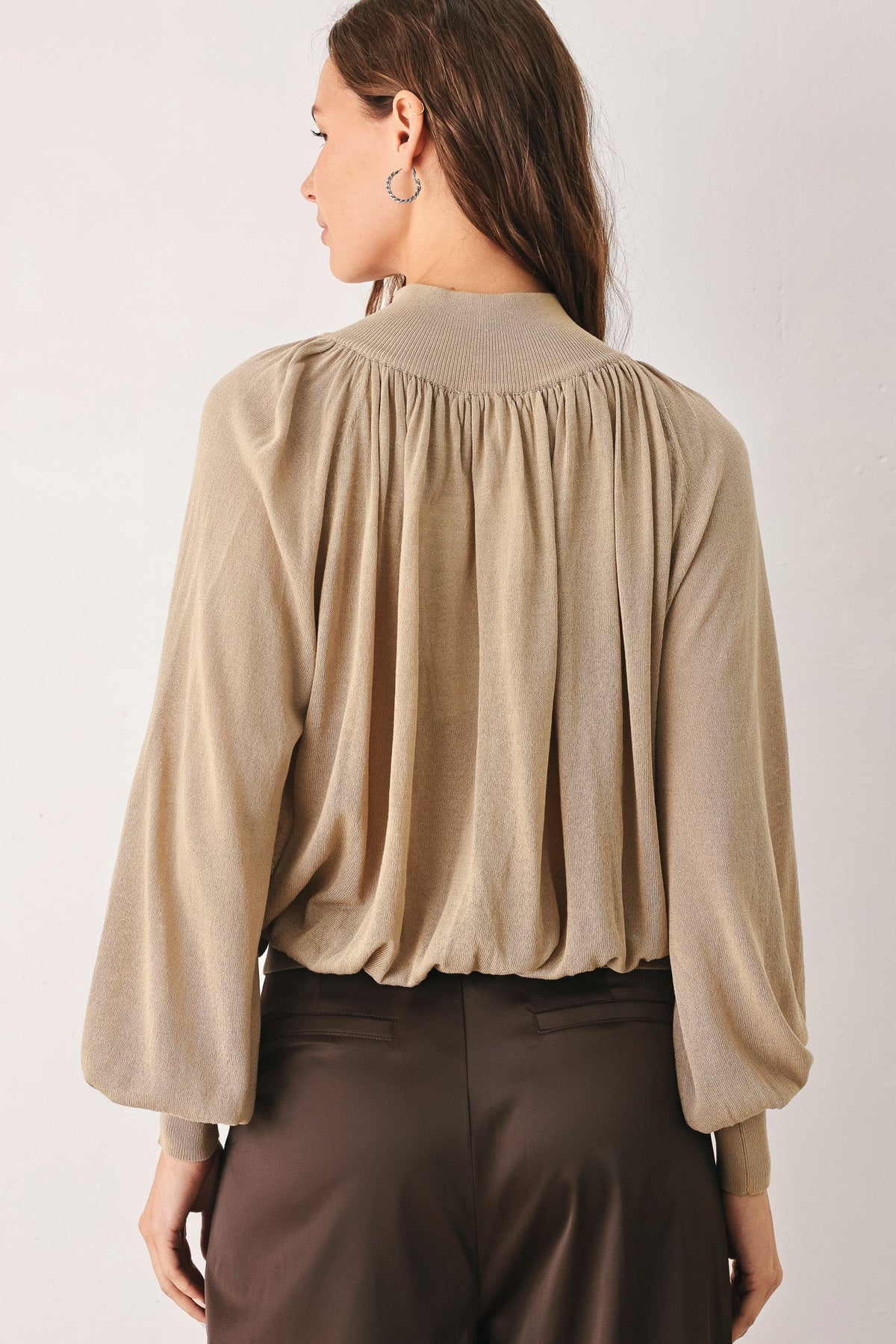 Back of taupe draped knit sweater top with gathered yoke and long sleeves