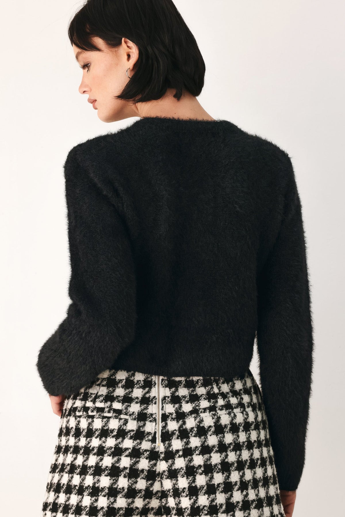 Black fuzzy cropped cardigan back view with rounded hem and long sleeves
