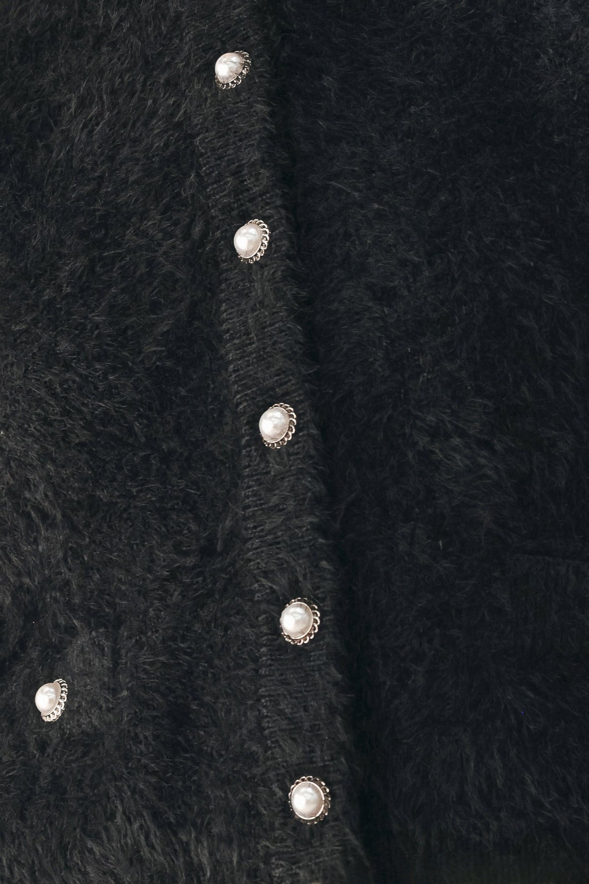 Black fuzzy cropped cardigan close-up of oval silver-tone front buttons
