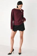 Burgundy cinched-neck sweater with long sleeves and gold charm at collar