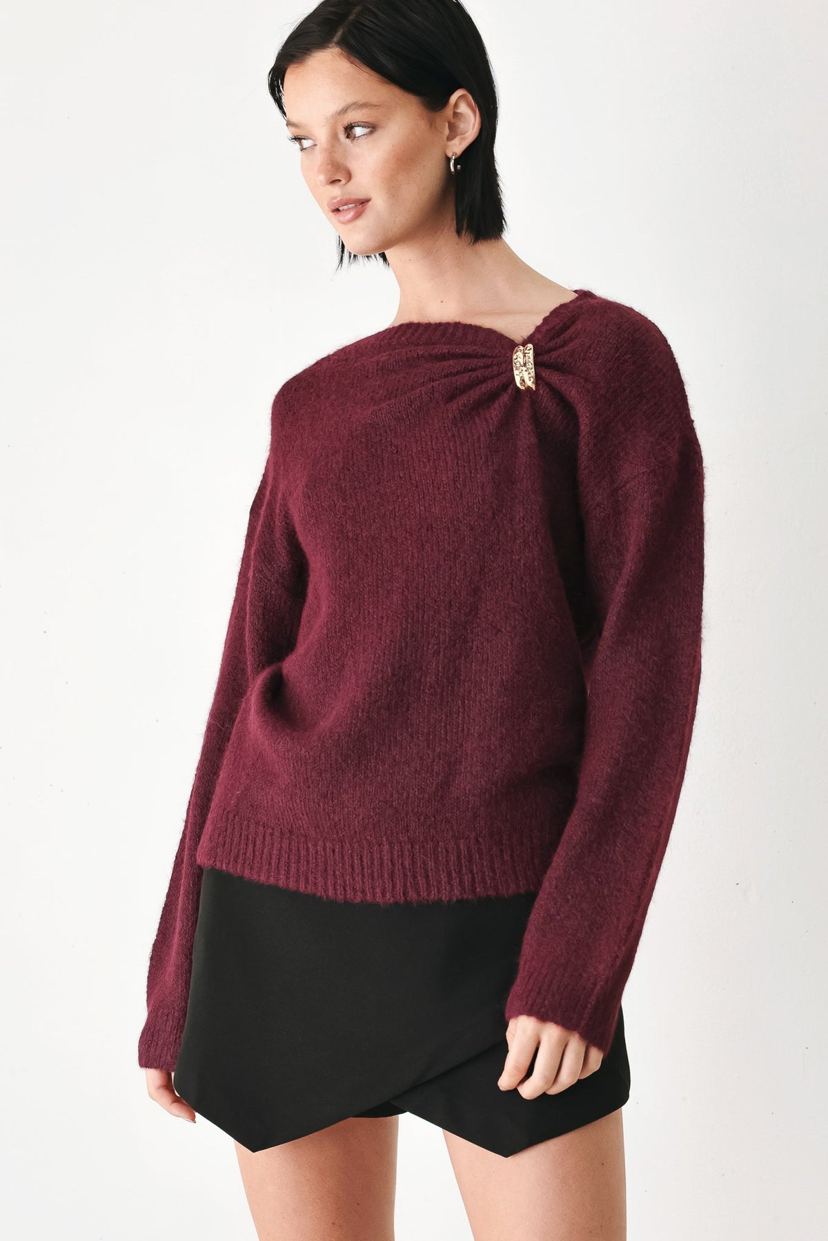 Burgundy sweater with cinched neckline and gold charm detail, long sleeves