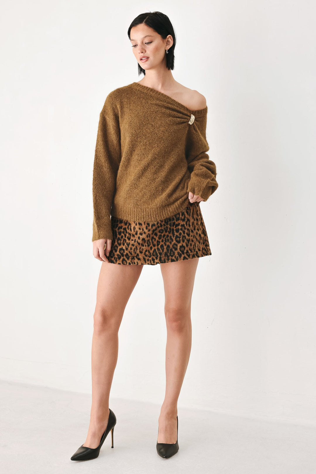 Camel-brown cinched neck sweater with one-shoulder neckline and decorative clasp