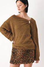 Camel-brown knit sweater with one-shoulder cinched neckline and decorative clasp