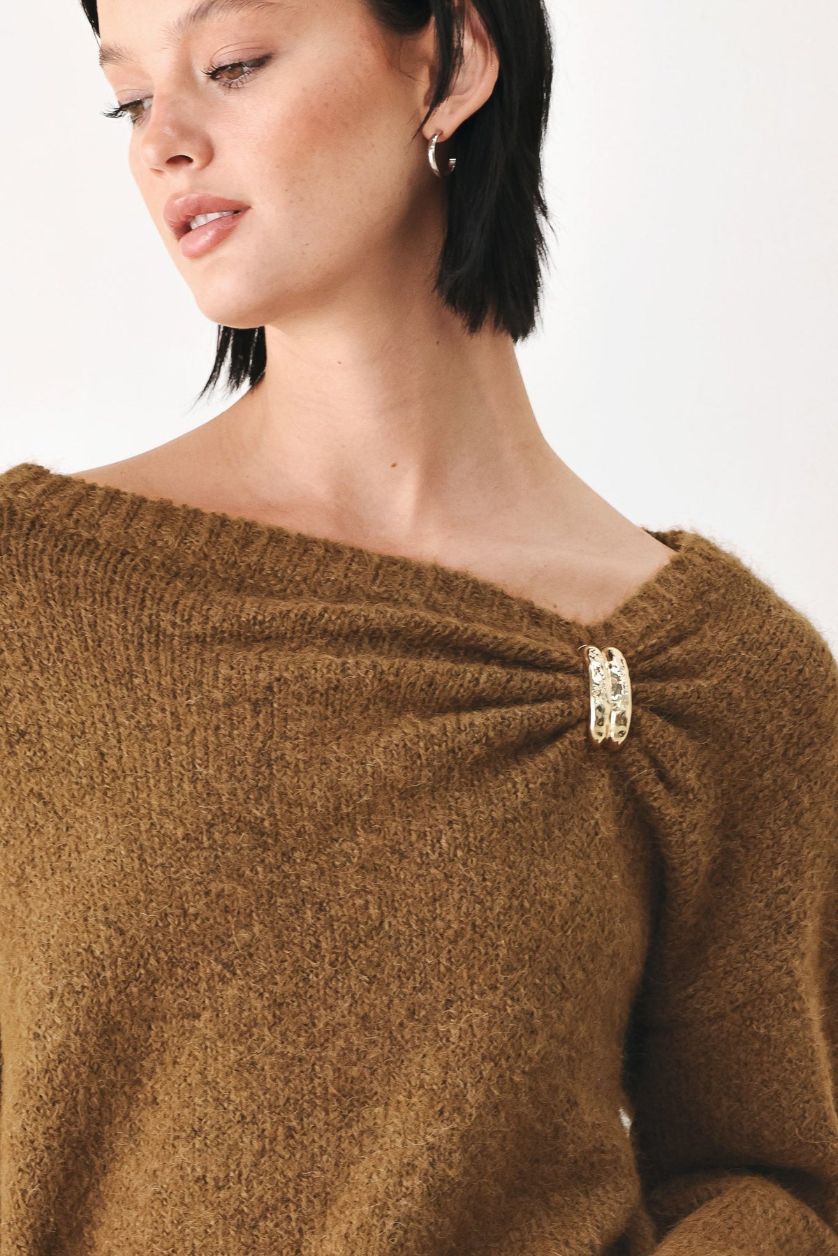 Camel-brown sweater featuring one-shoulder cinched neckline with clasp detail