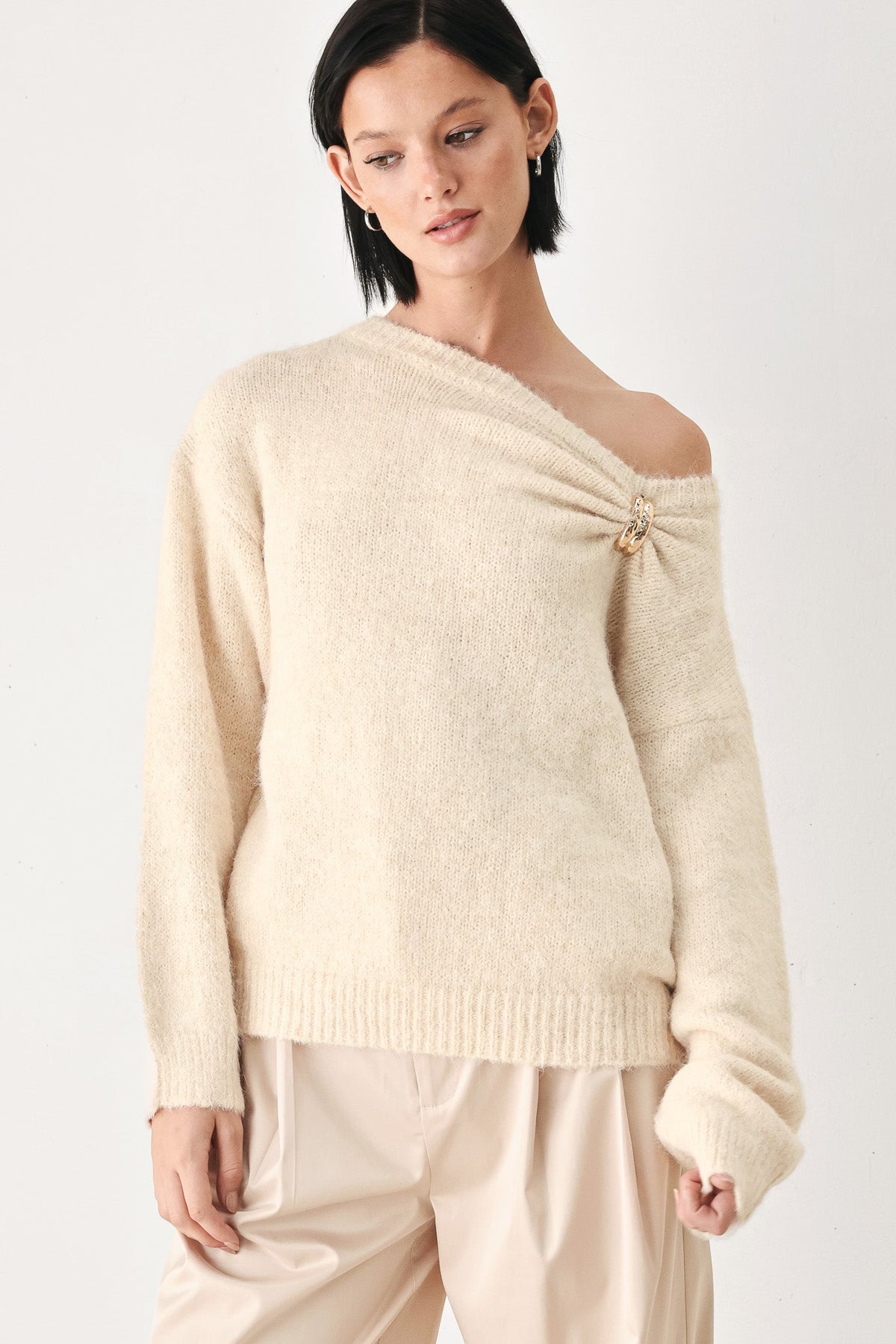 Ivory cinched neck sweater with off-shoulder neckline and decorative clasp