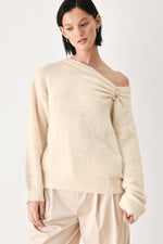 Ivory cinched neck sweater with off-shoulder neckline and decorative clasp
