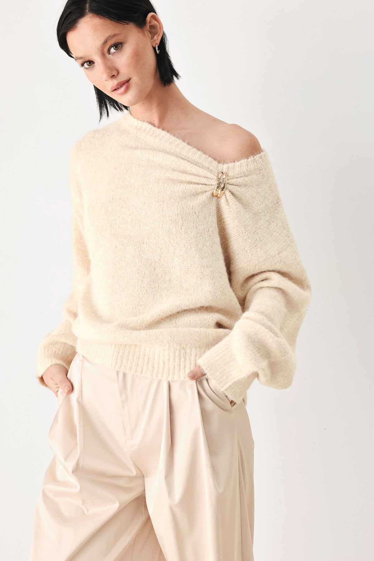 Ivory cinched neck sweater with off-shoulder neckline and clasp detail