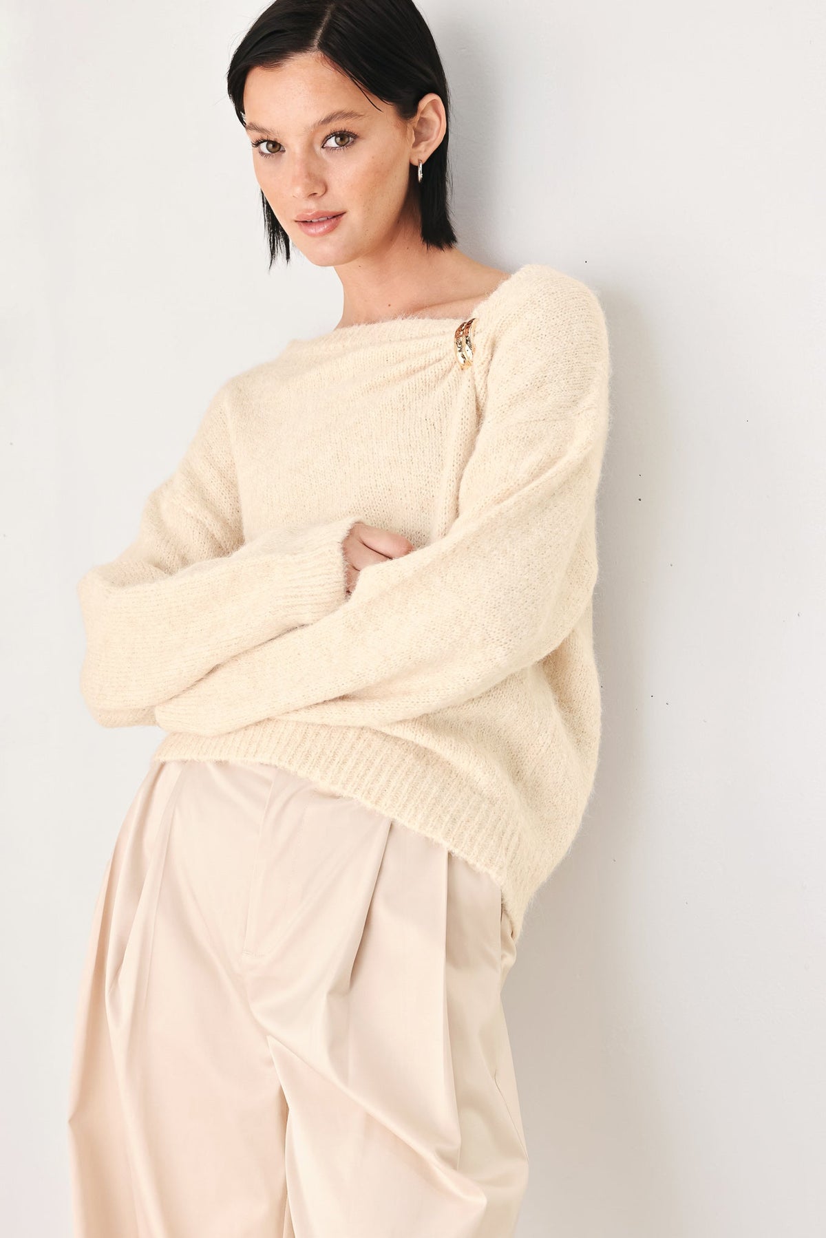 Ivory knit sweater with cinched neck and gold charm detail