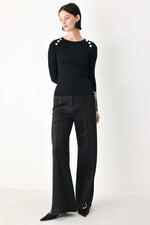 Black ribbed knit sweater top with crew neck, long sleeves, and shoulder button accents