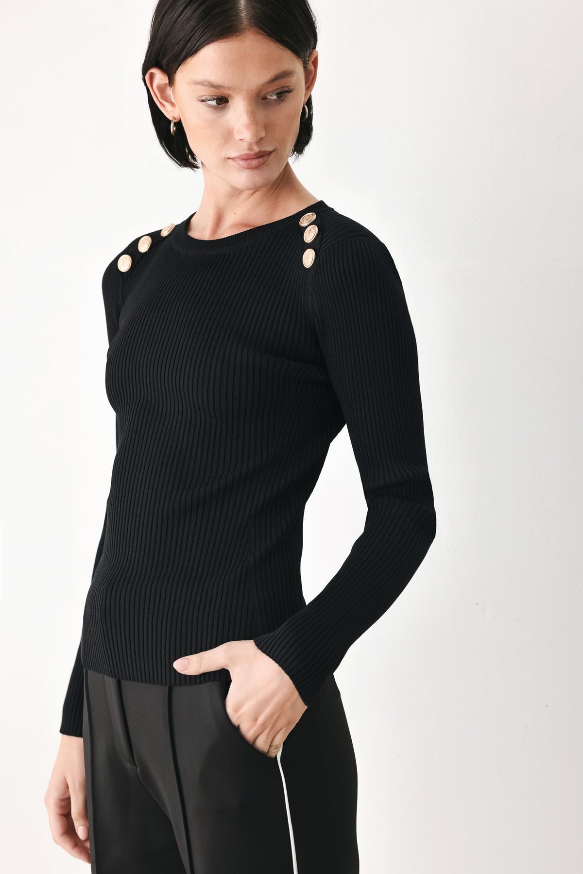 Black ribbed knit sweater top with crew neck and shoulder button accents, long sleeves