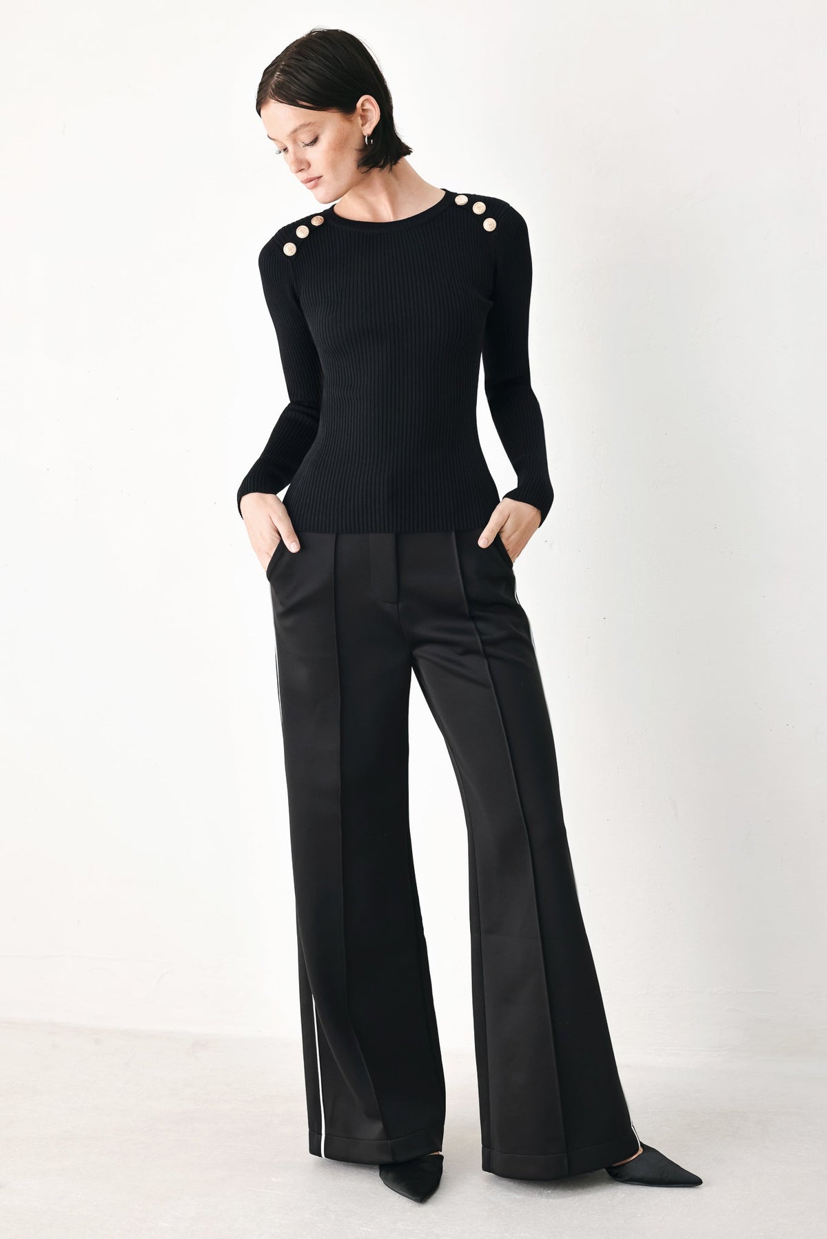 Black rib-knit classic sweater top with round neckline, long sleeves, shoulder buttons