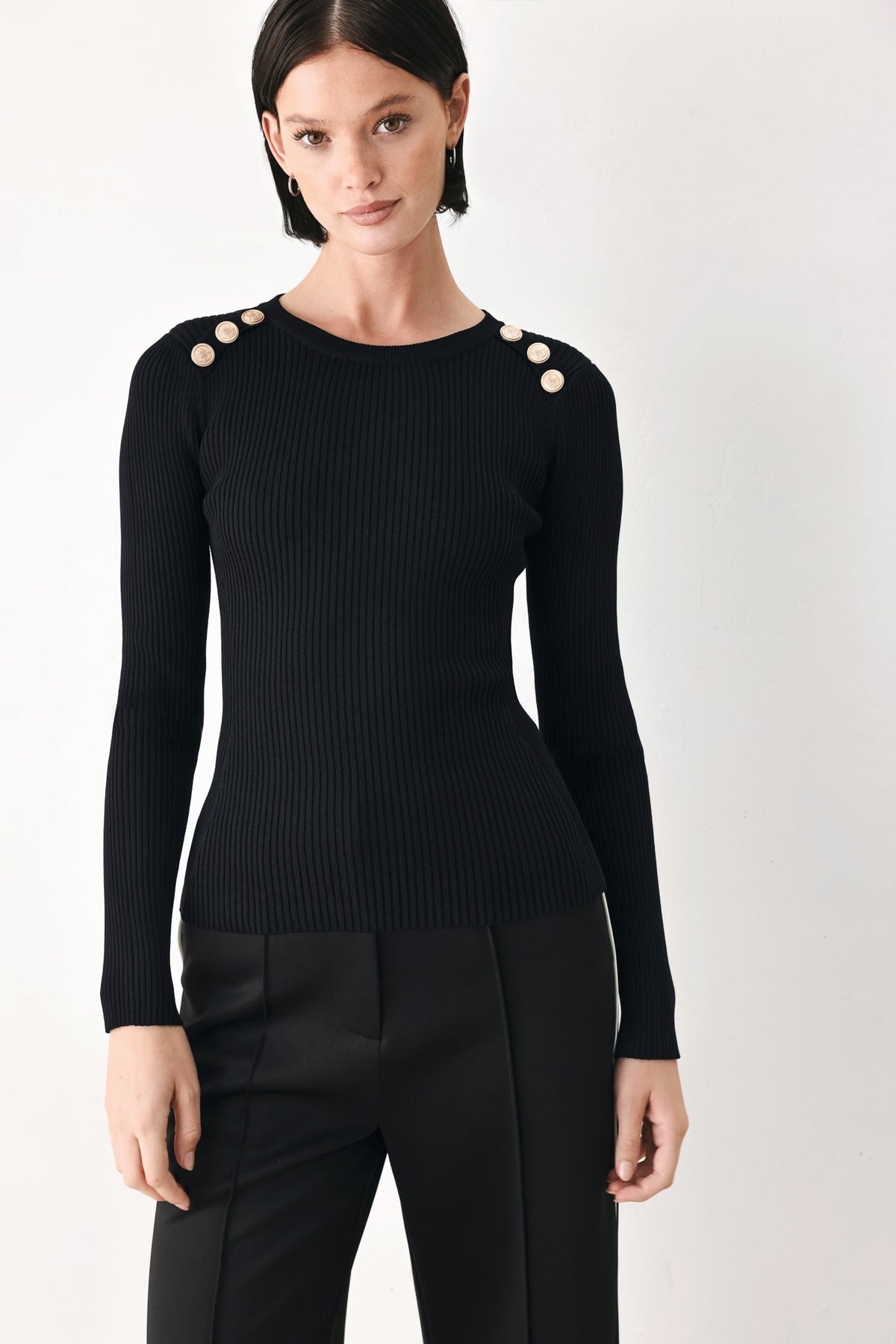 Black ribbed knit sweater top with crew neck, long sleeves, and shoulder button accents