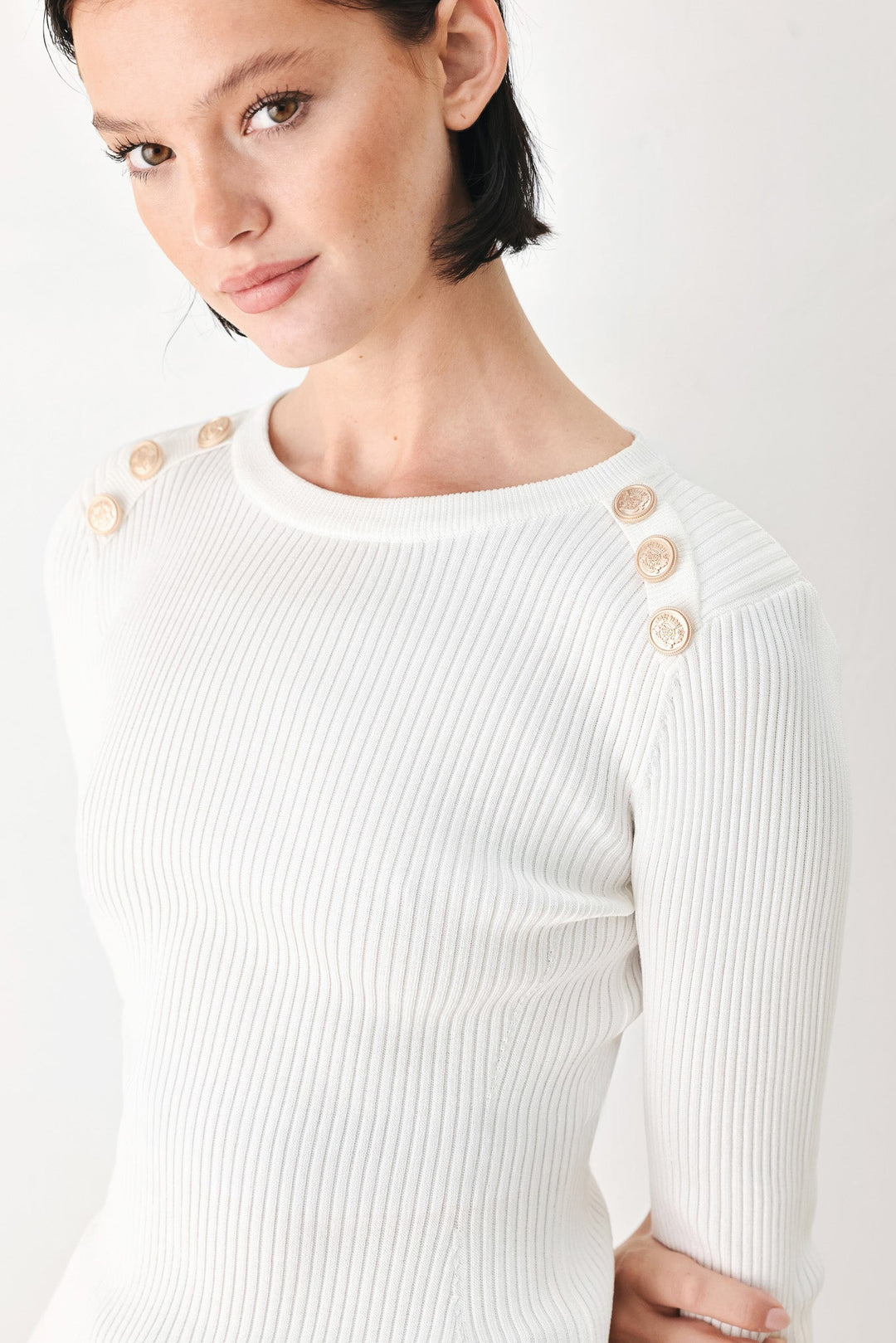 Off-white ribbed knit sweater top with crew neck and gold button details on shoulder