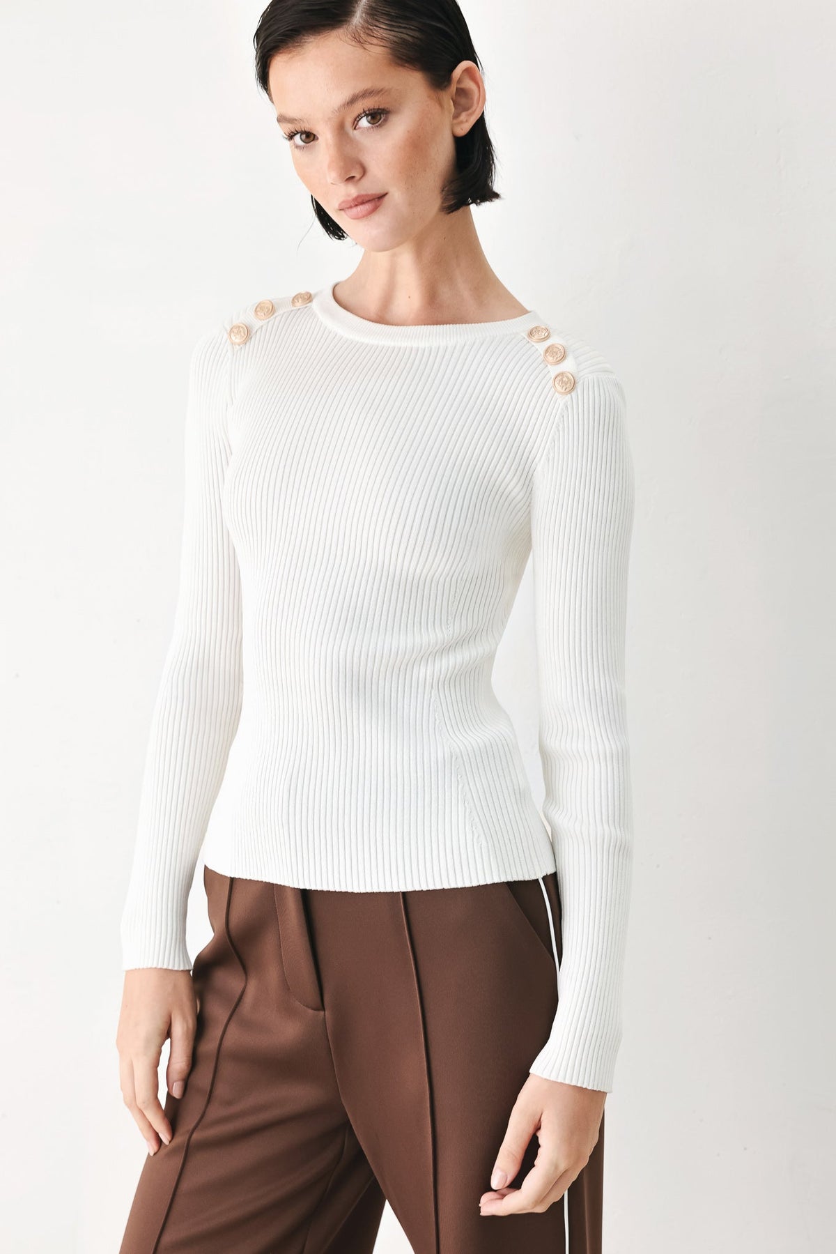 Off-white ribbed sweater top with crew neck, long sleeves, and gold button accents