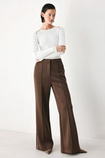 Off-white ribbed sweater top with crew neck and long sleeves, styled with dark wide-leg pants