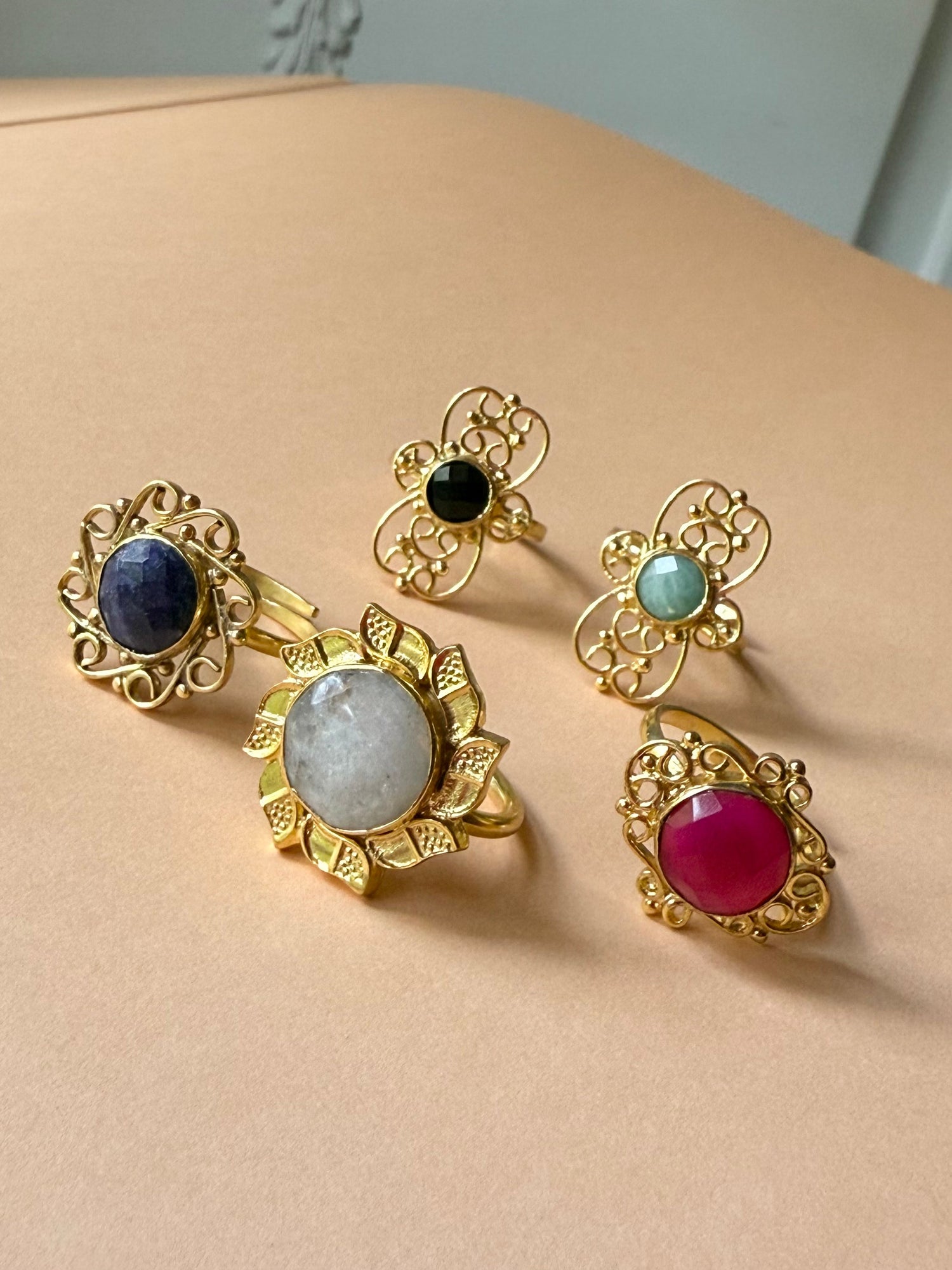 Gold-tone filigree gemstone ring set with blue, black, green, gray, and red stones