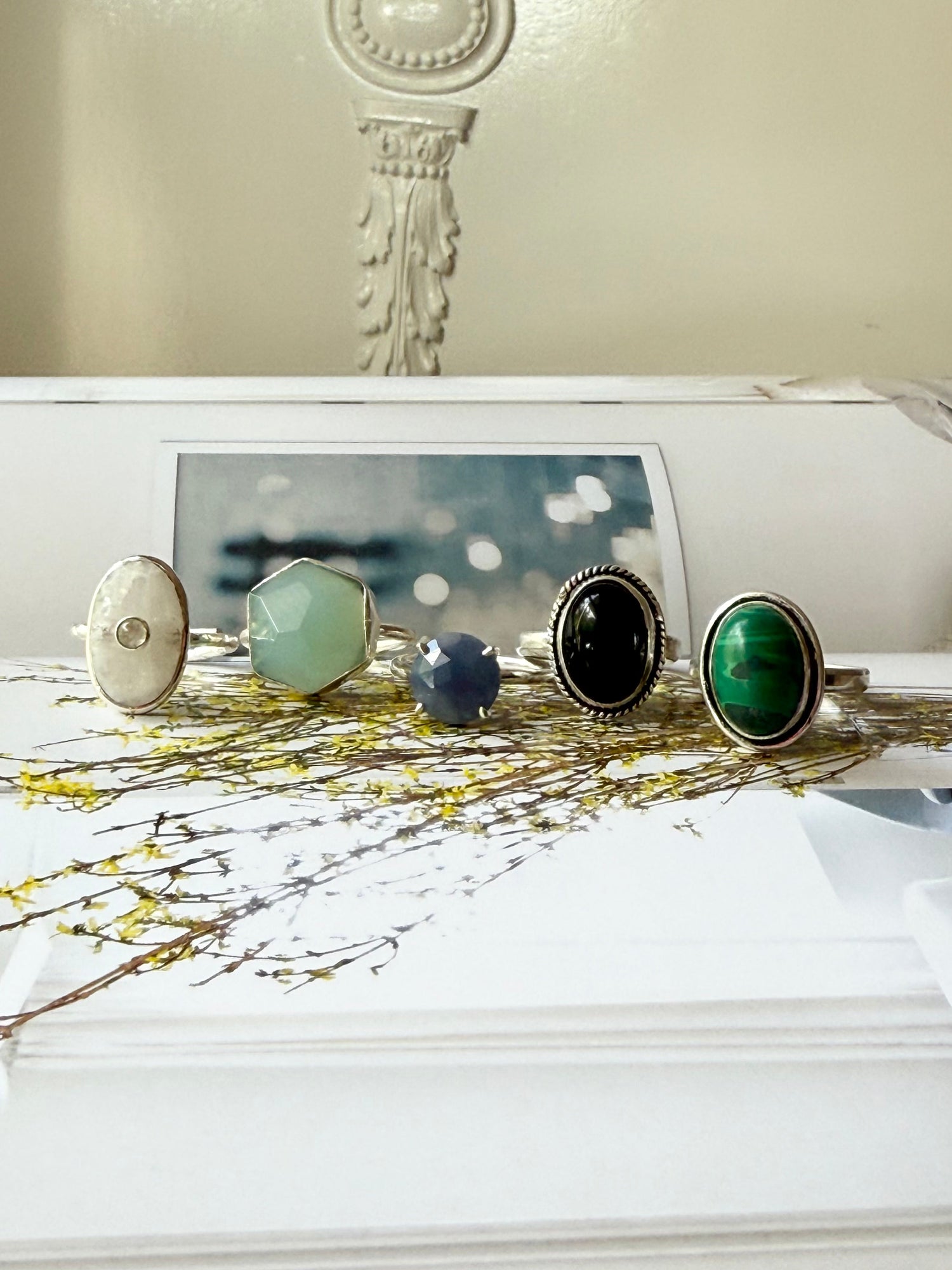 Gemstone ring set with green, blue, black, and teal stones on display stands