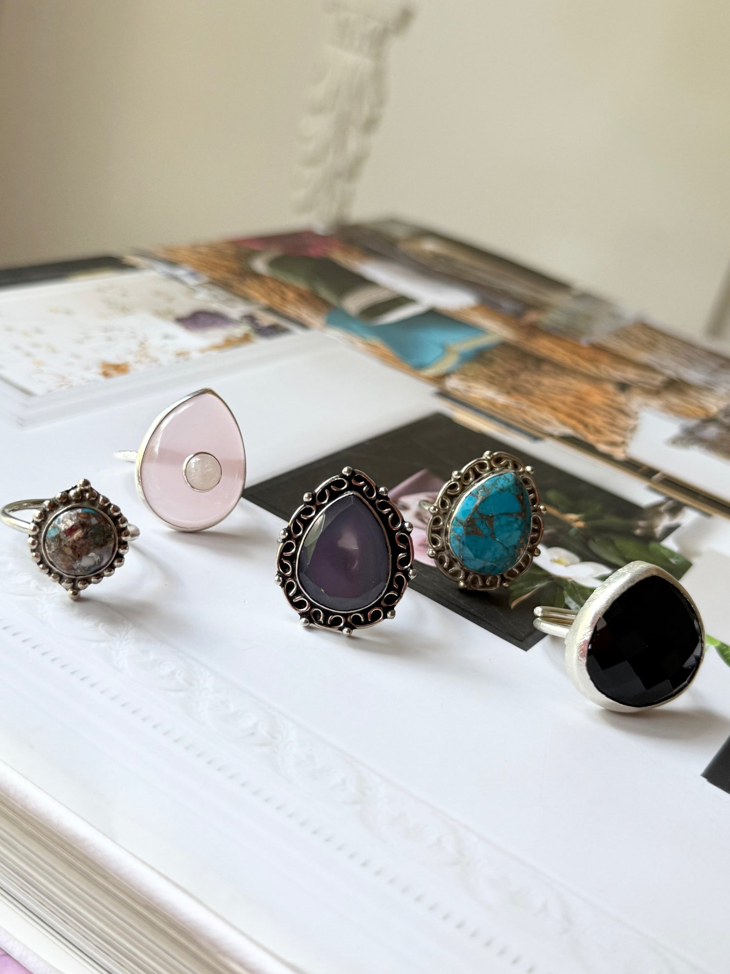Assorted statement rings with dark, purple, turquoise, black, and rose stones on metal