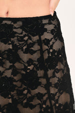 Black lace skirt detail with dense floral pattern and sheer mesh overlay