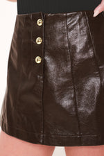 Dark brown faux leather skort with gold buttons and vertical seam stitching