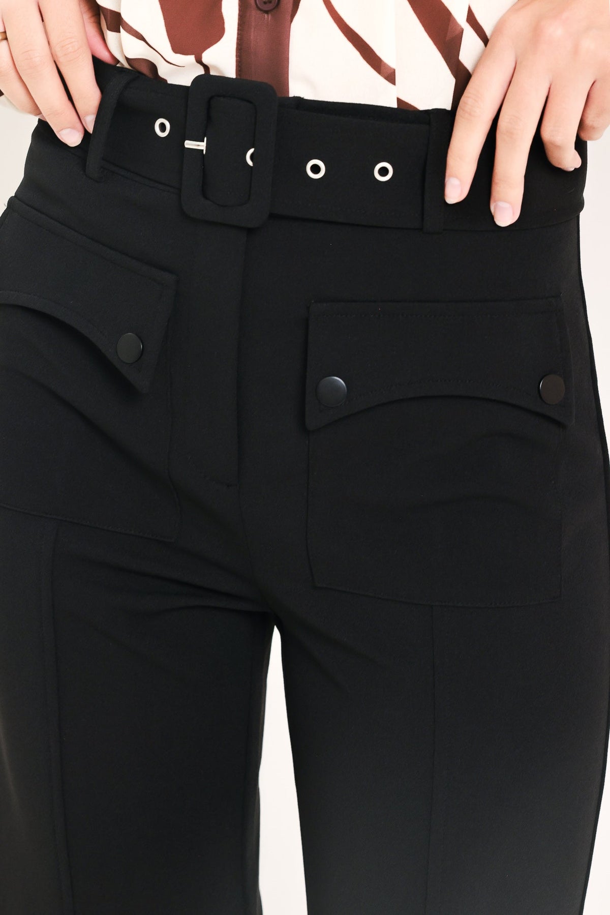 Black pants waistband with belt loops, snap button detail, and side pocket