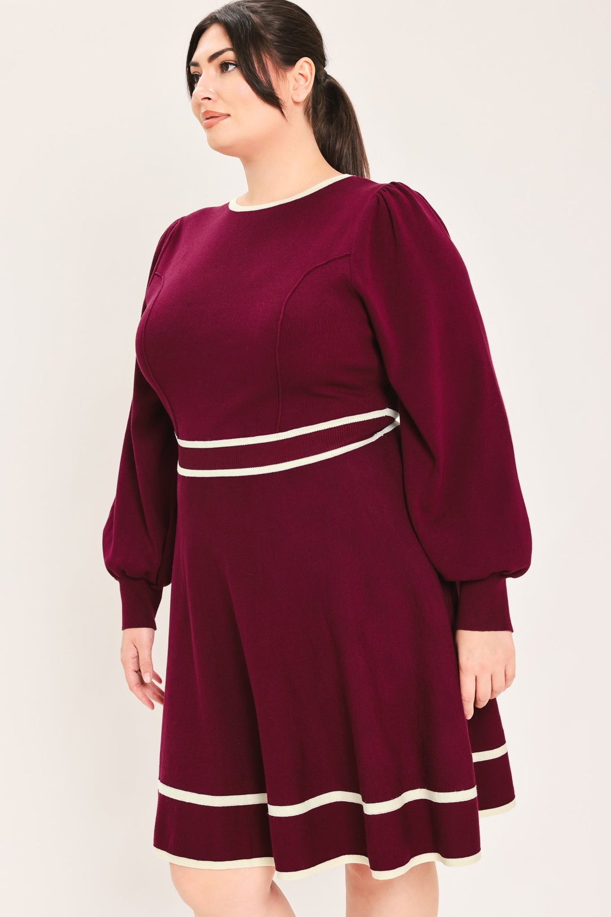 Side/back view of wine sweater mini dress with ivory stripe waistband and hem, puff sleeves