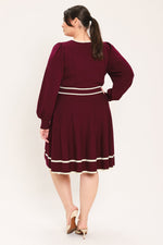Wine sweater mini dress back view with long puff sleeves and striped skirt hem.
