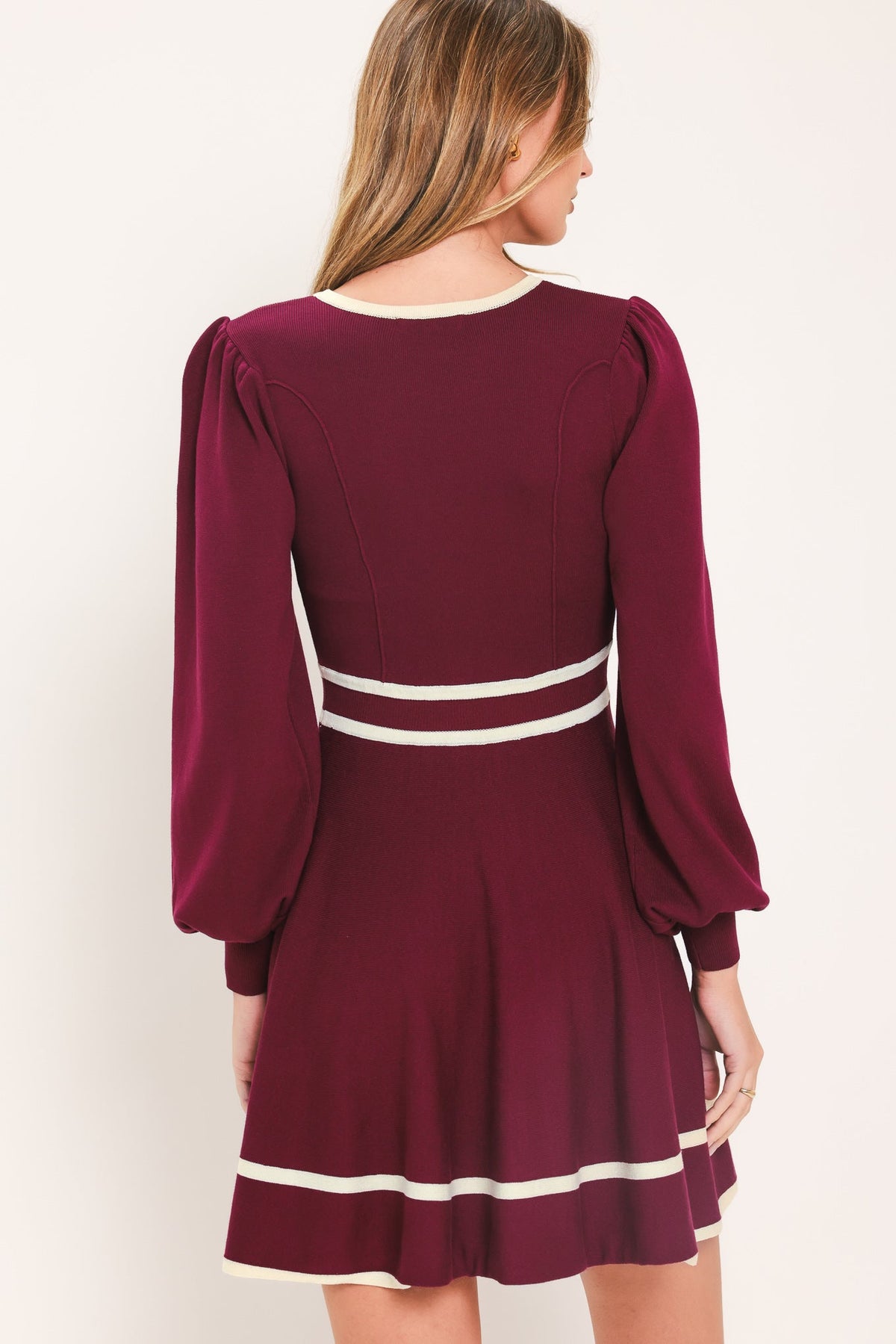 Back view of wine sweater mini dress with ivory stripe hem and three-quarter puff sleeves