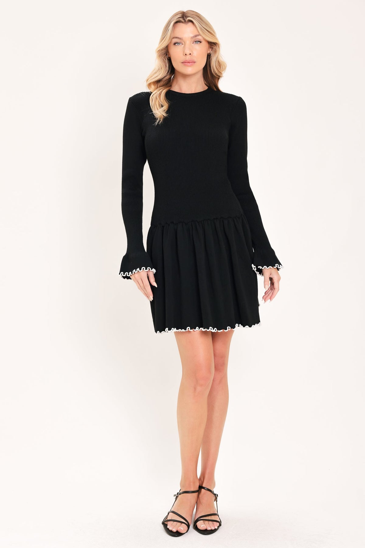 Black knit mini sweater dress with tiered skirt and white scalloped trim at hem