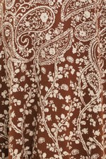 Camel-brown jacquard knit fabric with ornate white paisley motifs