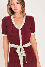 Close-up of burgundy ribbed knit button-down midi dress with cream V-neck and waist tie