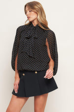 Black woven top with gold dot print, bow-tie collar and long puff sleeves