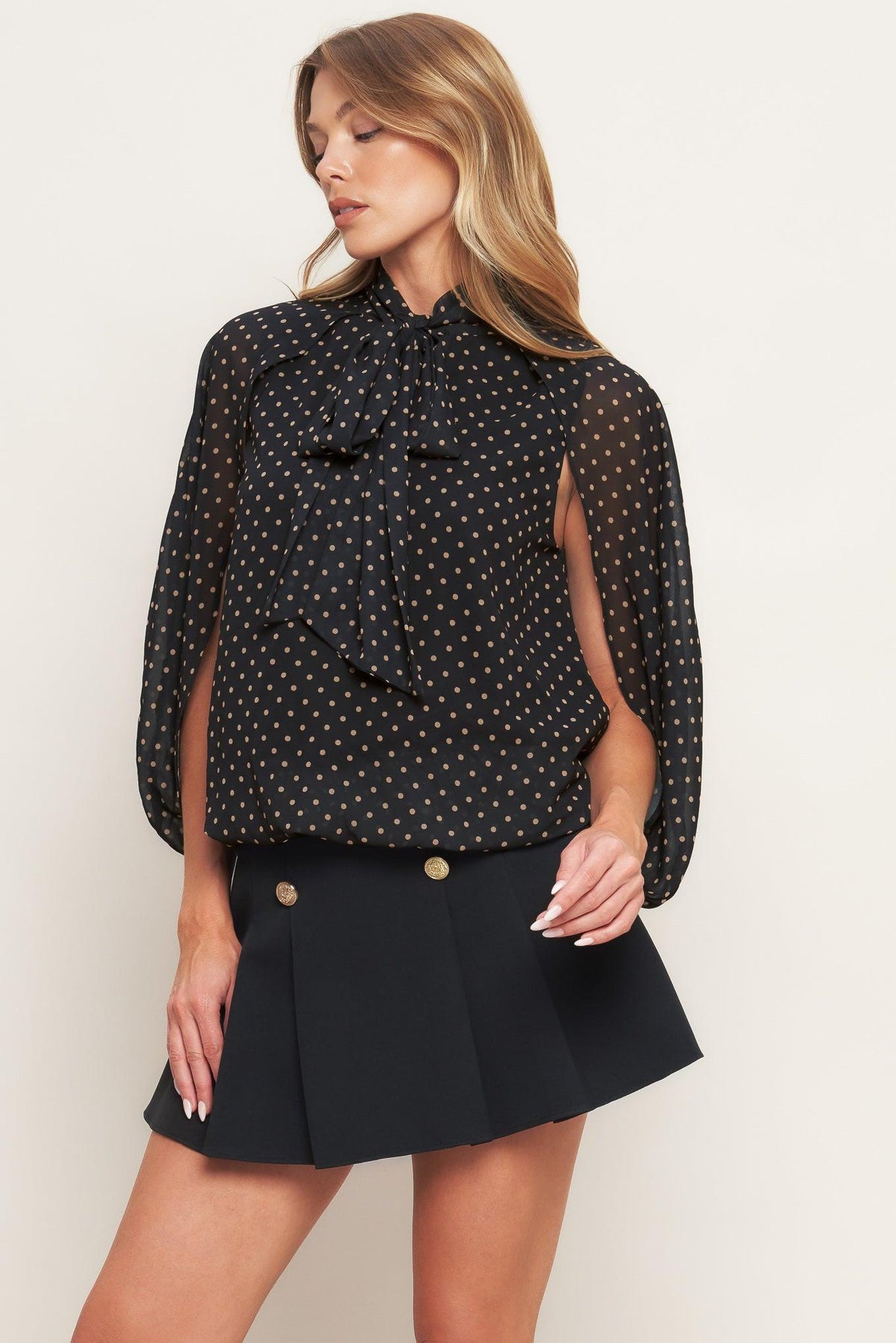 Black woven top with gold dot print, bow-tie collar and long puff sleeves