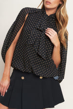 Black woven top with gold dot print, layered bow detail at chest