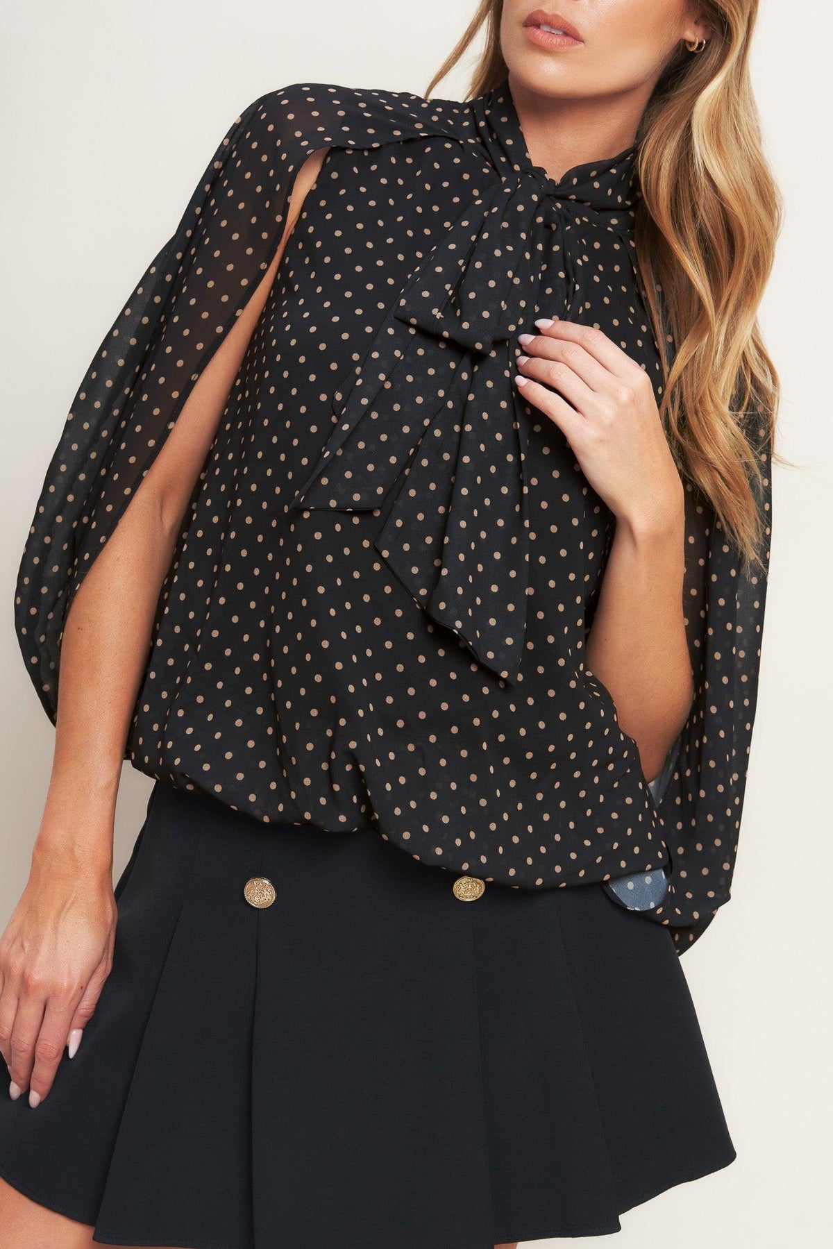 Black woven top with gold dot print, layered bow detail at chest