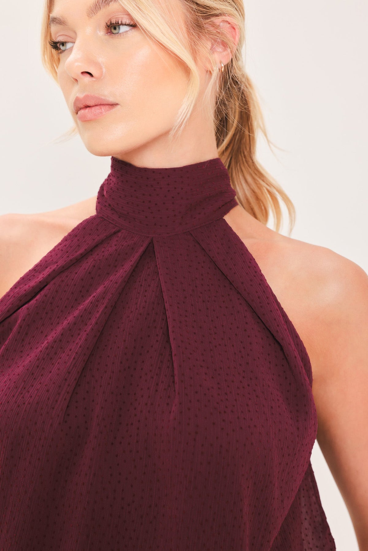 Close-up: burgundy sheer halter top with high neck and bow-tied drape detail