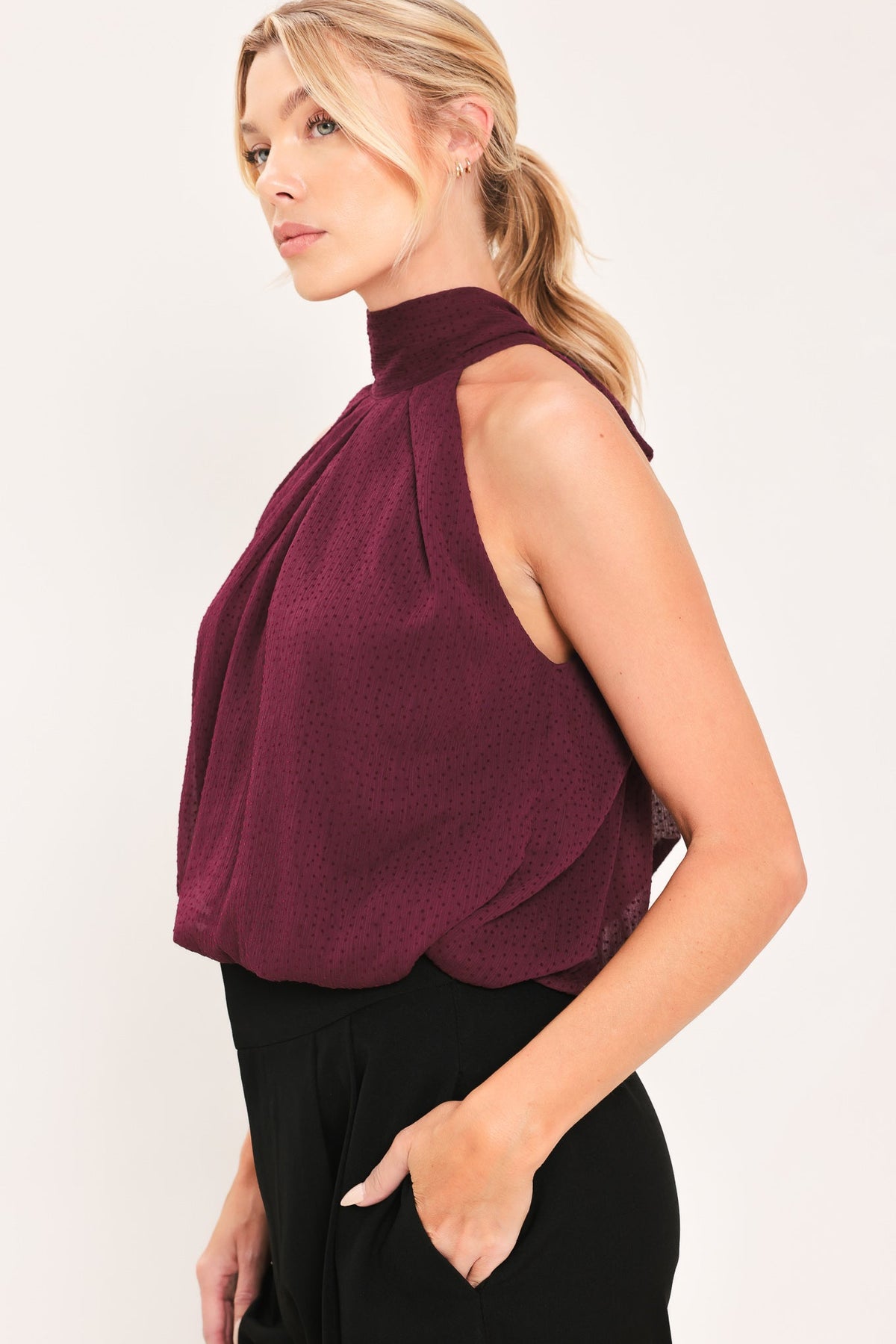 Side view burgundy sheer drape halter top with sleeveless cut and pleated front