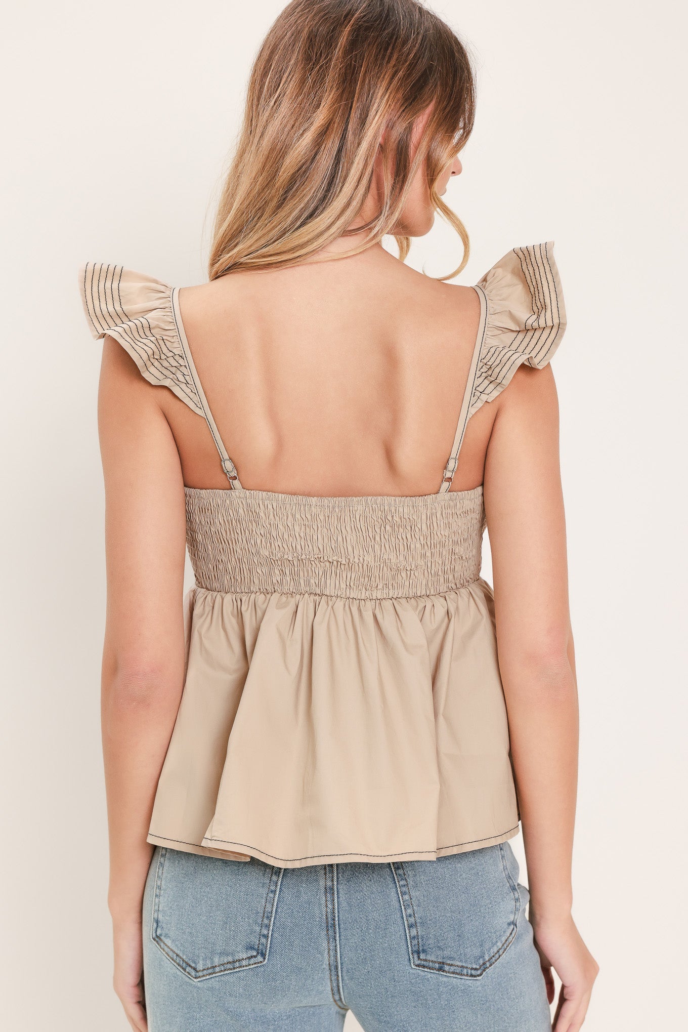 Neutral woven flutter top, back view with V-back, gathered waist and flared peplum hem