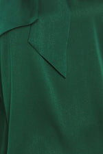 Close-up of hunter green satin tie-neck top fabric with seam and panel stitching