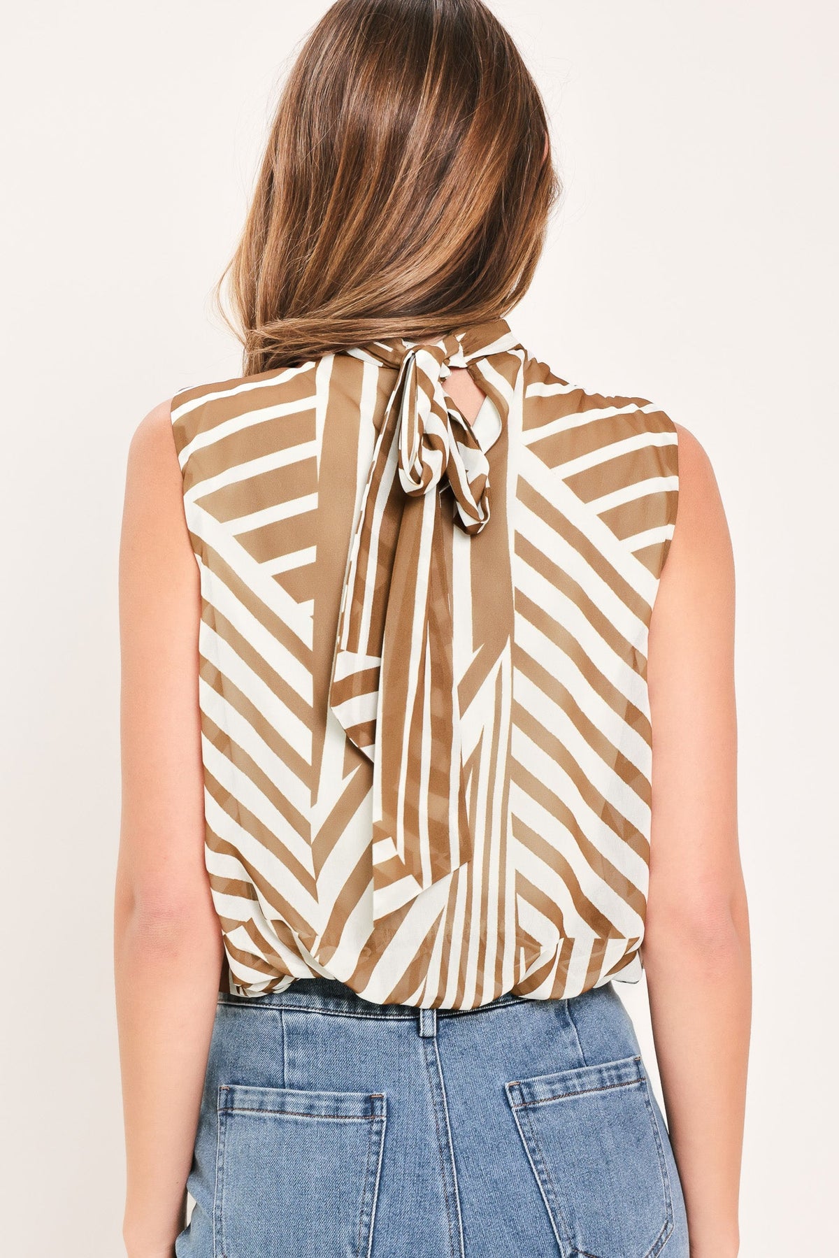 Back view of mocha striped woven sleeveless top with high neck and bow tie