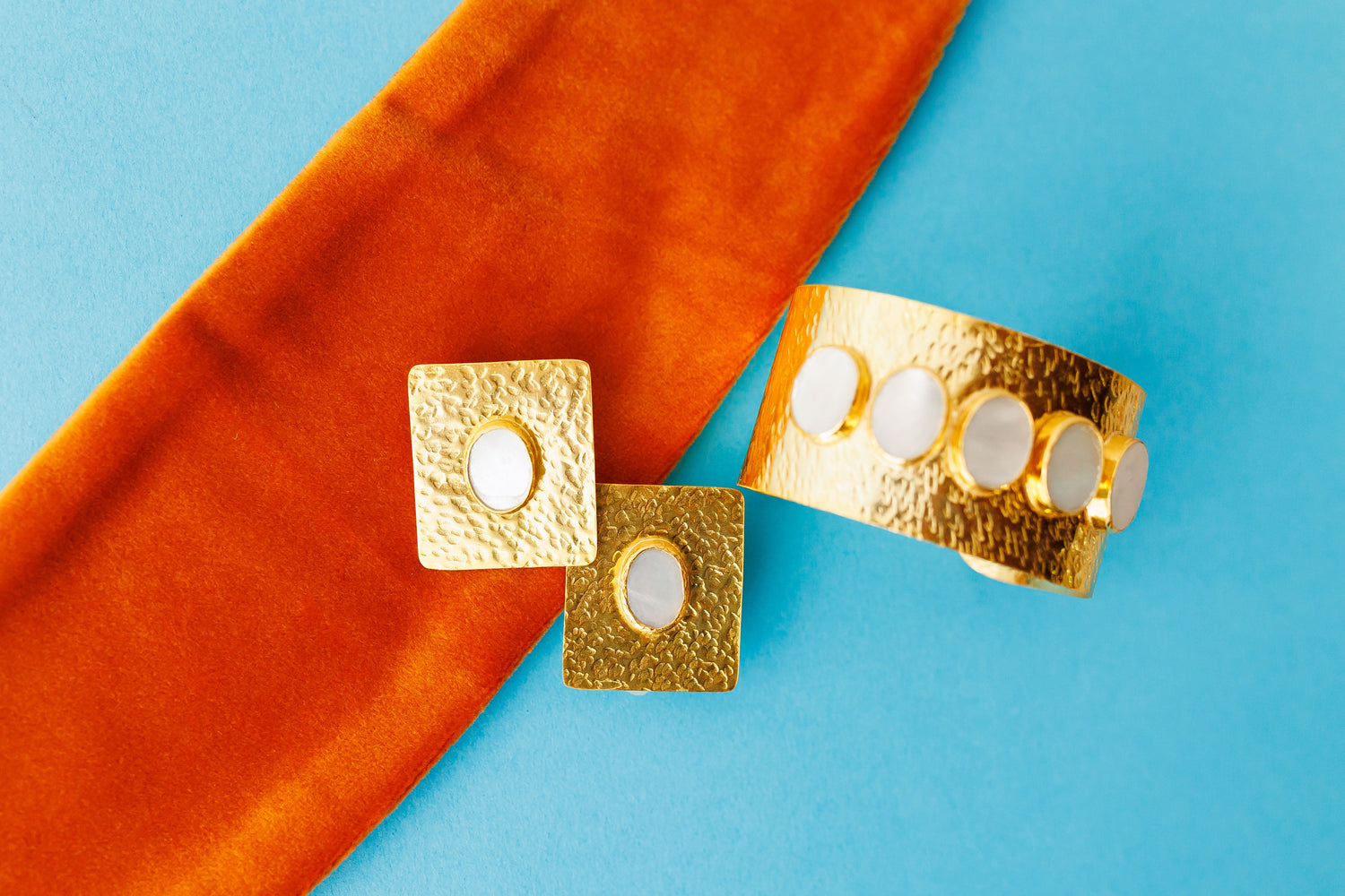 Set of gold square stud earrings with oval cutout and hammered finish.