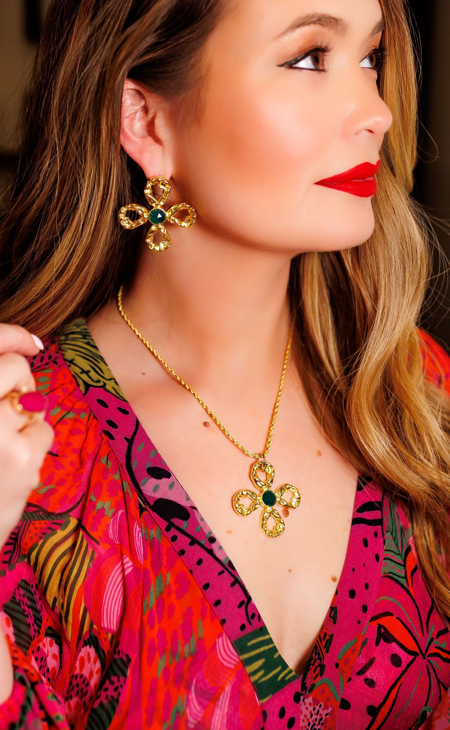 Gold-tone necklace with quatrefoil pendant and dark green center bead, side view.