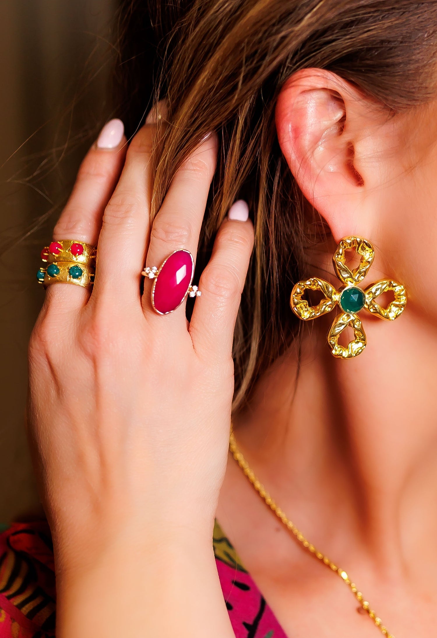 Fuchsia oval ring on a gold band, worn with small clear stone details