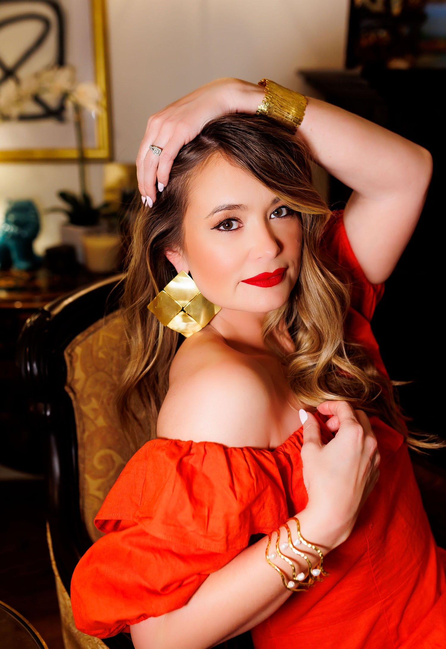 Gold geometric drop earrings with hammered square detail, worn with red off-shoulder top