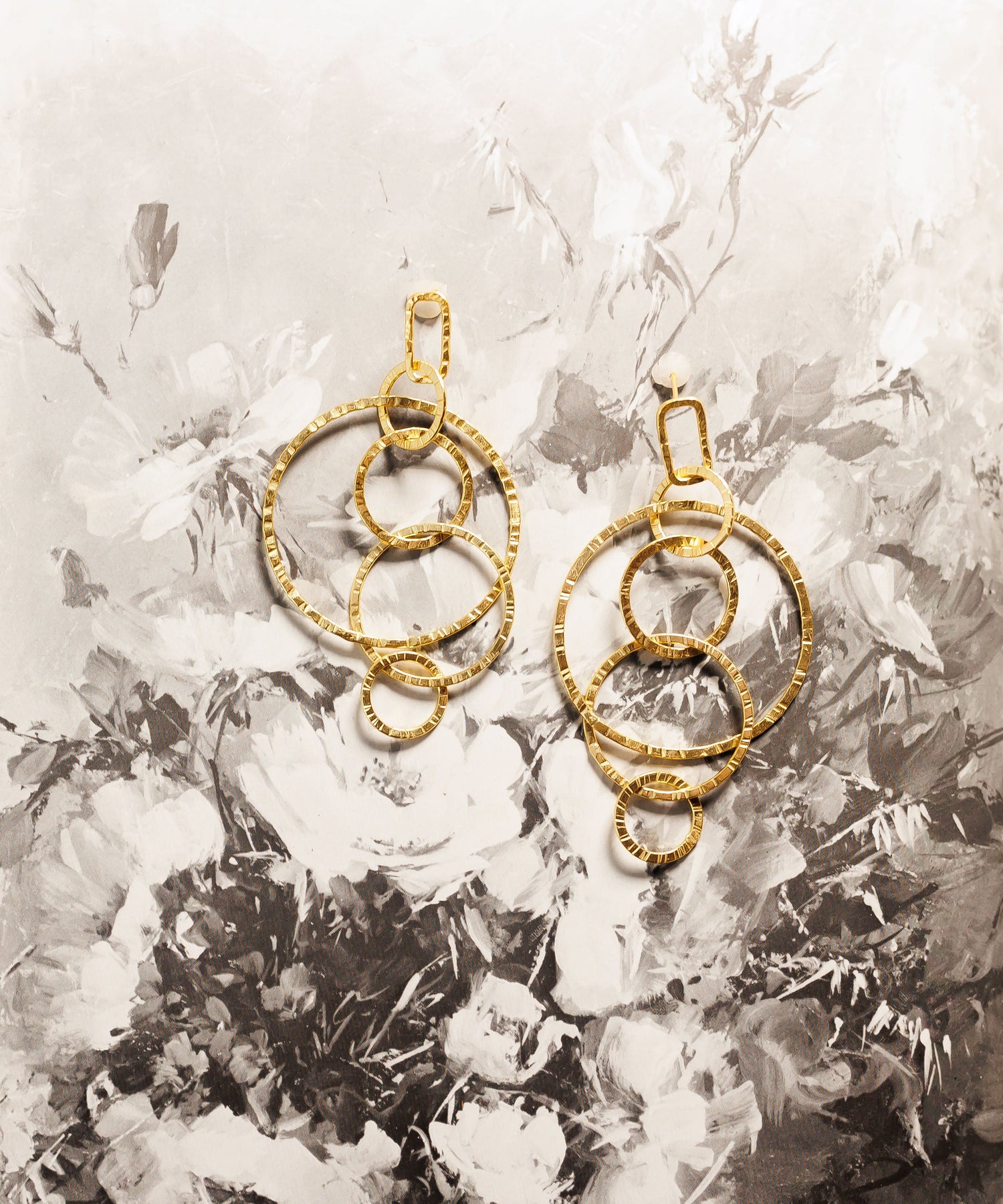 Pair of gold circular hoop earrings with beaded accents and dangling top loop