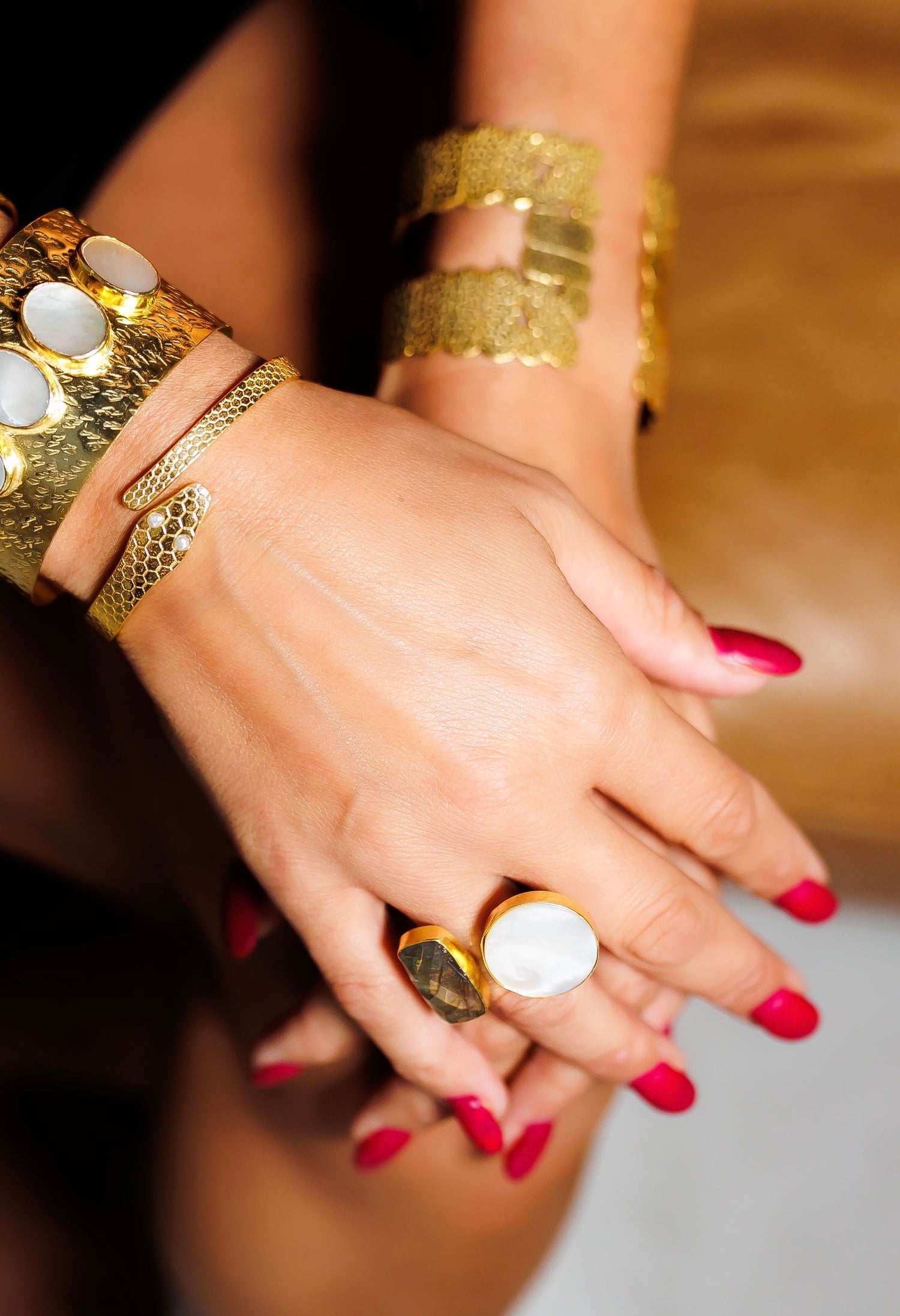 Gold ring with white oval stone on finger, textured lattice band with openwork design