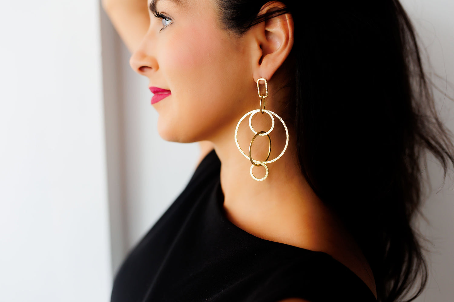 Gold circle hoop earrings with three stacked loops and dangling charm
